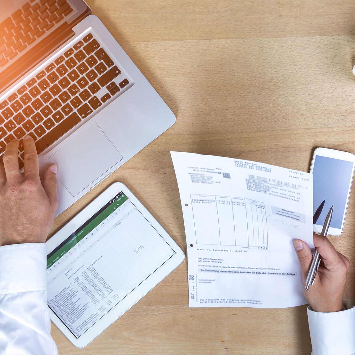 Ein Geschäftsmann arbeitet an Dokumenten und einem Laptop.